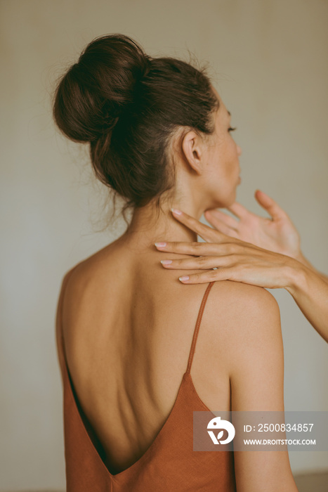 Female hands gently touch the young attractive brunette woman.