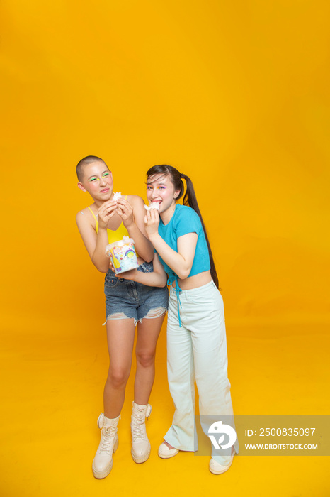 Studio portrait of smiling stylish friends eating cotton candy