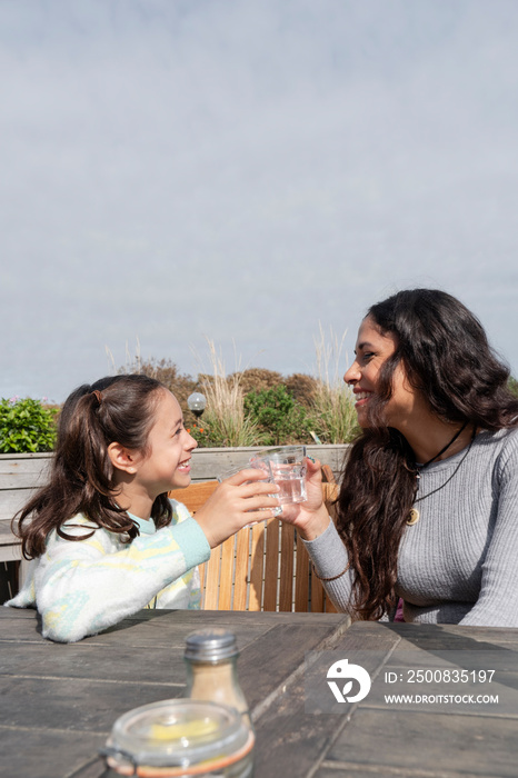 Mother and daughter drinking water in outdoor restaurant