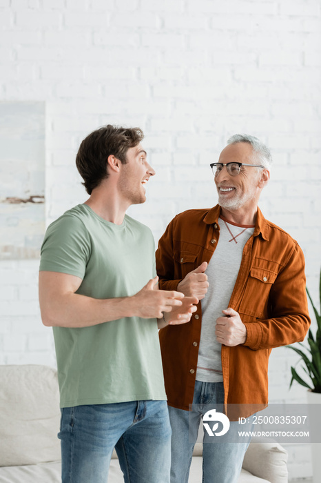 happy young man talking with smiling mature father in eyeglasses at home