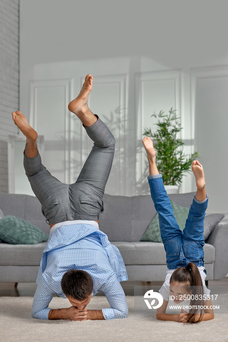 father copy imitate active child girl doing gymnastic handstand exercise