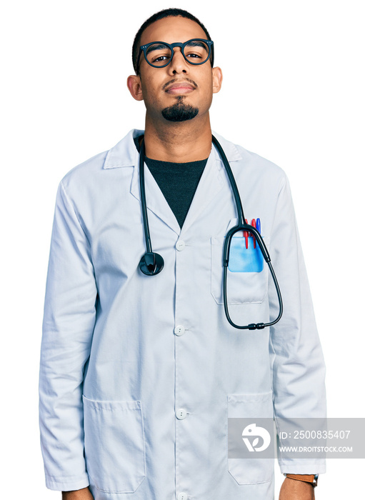 Young african american man wearing doctor uniform and stethoscope relaxed with serious expression on face. simple and natural looking at the camera.