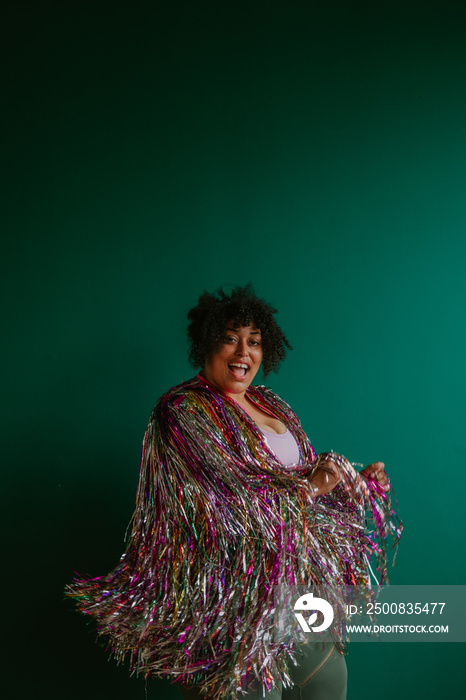 portrait of a person with a rainbow tinsel jacket laughing