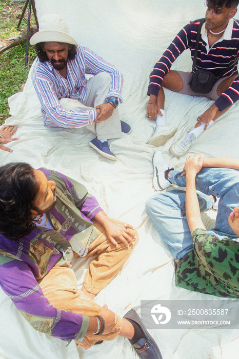 Malaysian Indian men posing and laughing together in a group setting, outdoors, in a park against a cloth backdrop