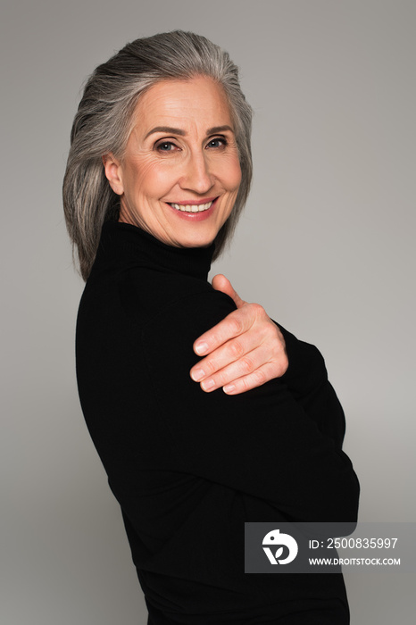 Portrait of woman in black jumper smiling isolated on grey