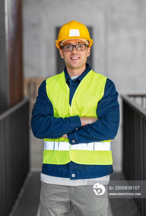 architecture, construction business and building concept - happy smiling male architect in helmet and safety west at office