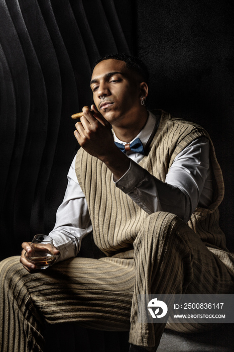 Portrait of a serious young black man looking at his cigar
