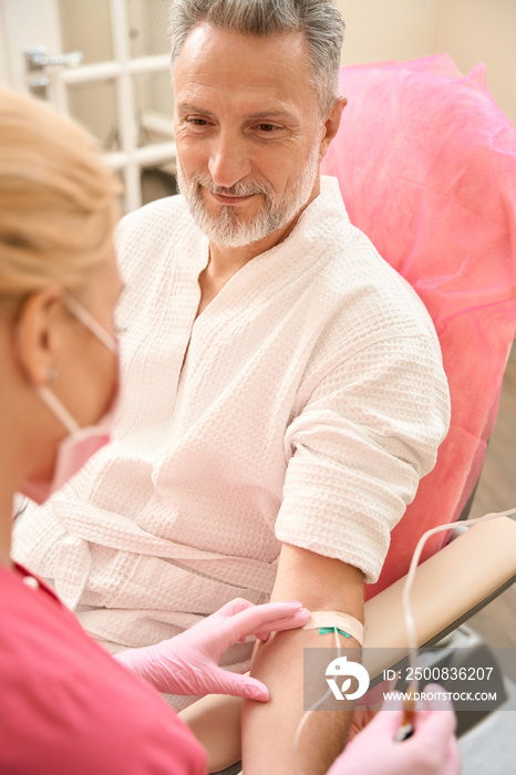 Middle-aged man is having an intravenous procedure in hospital