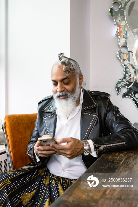 man with gray hair and beard looking at smartphone