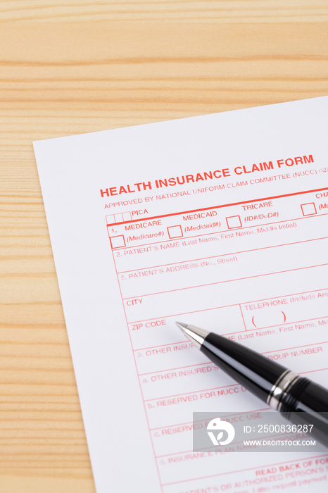 Health insurance claim form with pen on wooden desk