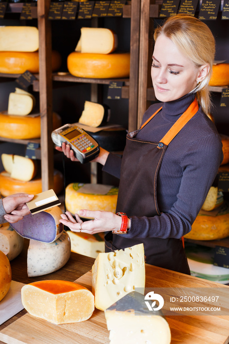 Customer paying for order of cheese in grocery shop.