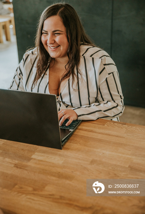 plus size woman types on keyboard and smiles