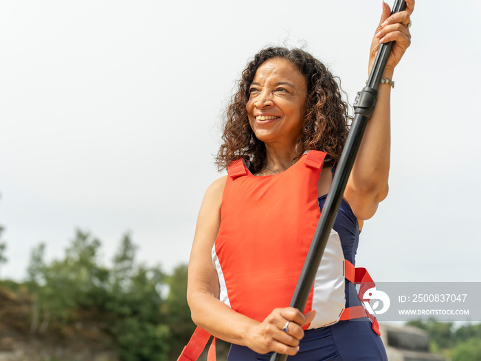 Portrait of smiling woman standing with oar