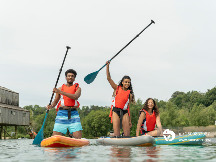 Friends having fun while paddleboarding on lake