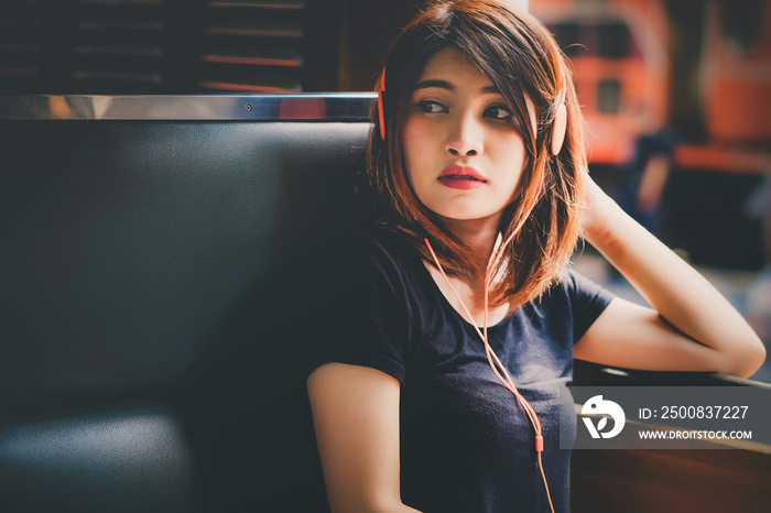 Asian young girl sitting by the window of the train and listening to music. traveler tourists travel city street, journey backpack adventure outdoor by train