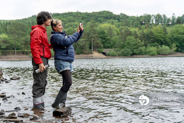 Mother and son wading in lake and taking selfie