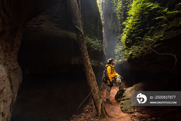 Rescue hiker with backpack climbs natural rocky wall. Wearing in climbing equipment rope carabiner