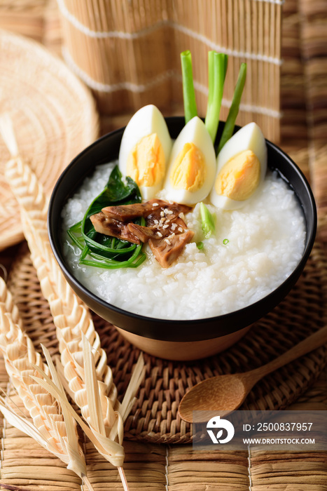 Asian food, Rice soup with boiled egg, grilled mushroom and spinach in a bowl on woven rattan sheet