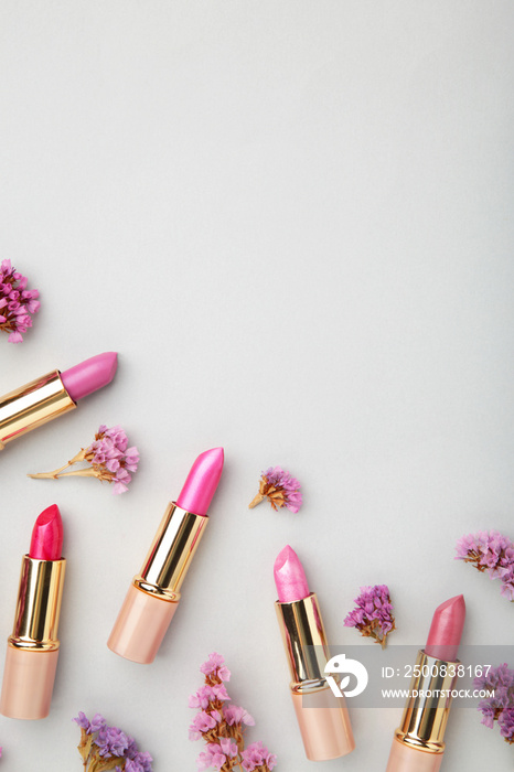 Lipstick with beautiful flowers on grey background with copy space. Vertical photo