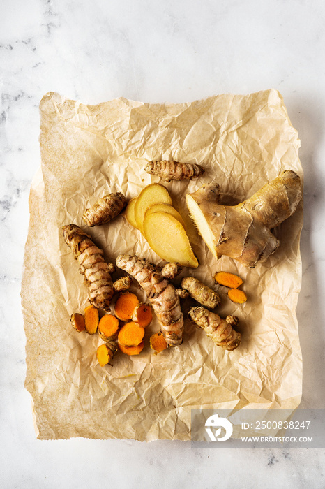 Top view of turmeric roots and ginger on crumpled paper