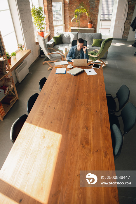 Creative workplace - organized work space as you like for inspiration. Man working in office in comfortable attire, relaxed position and messy table. Choose atmosphere you want - ideal clear or chaos.