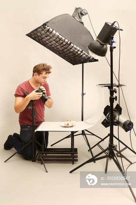 Male photographer in studio shooting food on plate