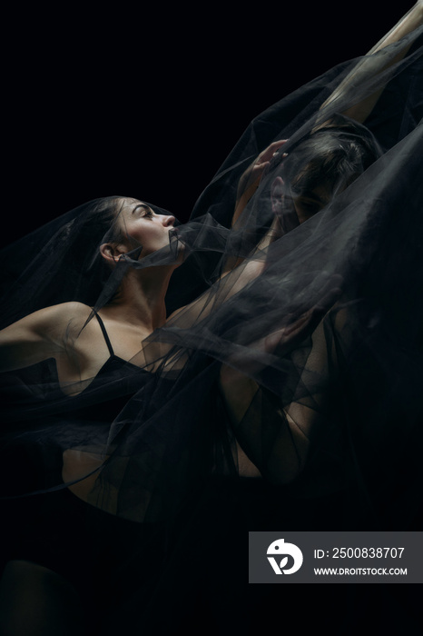Passion. Graceful classic ballet dancers isolated on black studio background. Couple in minimalistic dark cloth look graceful, inspired. The grace, artist, movement, action and motion concept.