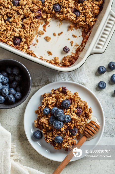 Baked oatmeal with blueberries and honey in on white plate, top view. Oatmeal fruit crumble pie.