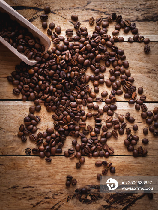 Coffee beans and scoop on wooden background, top view