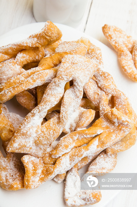 Faworki - Traditional Polish cookies served at Fat Thursday.  Cookies and tulip bouquet on white wooden background