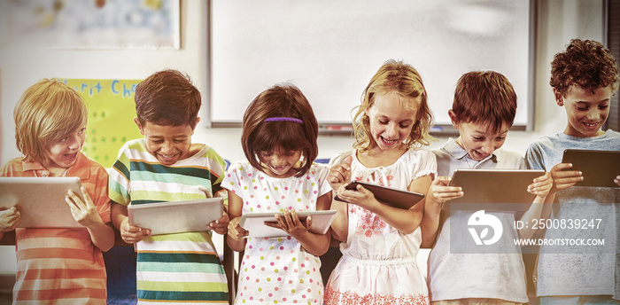 Smiling schoolchildren using digital tablets