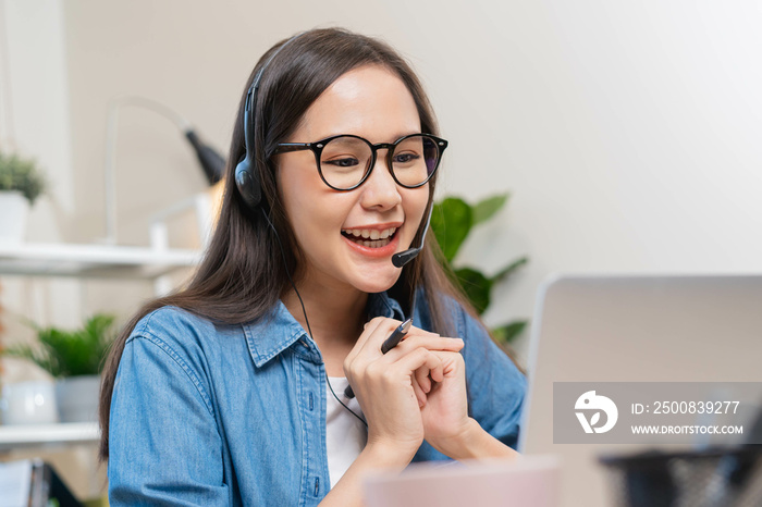 Video call, meeting conference via camera, happy pretty asian young woman, girl sitting, wear wireless headphone study online, using laptop computer, freelancer working.Technology, social distance.