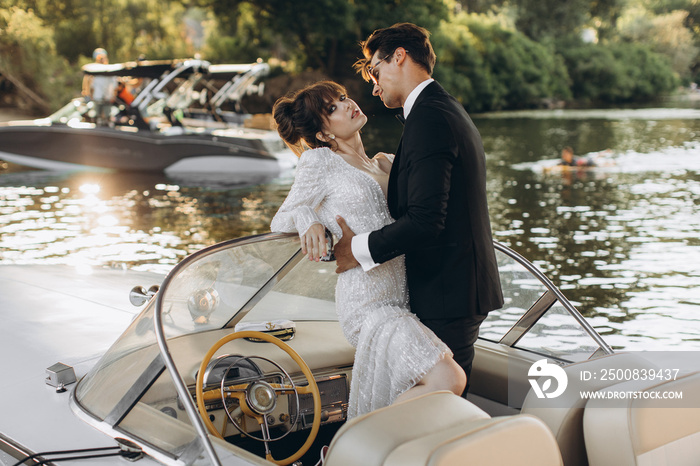 Stylish young bride and groom huging and kissing on board the yacht