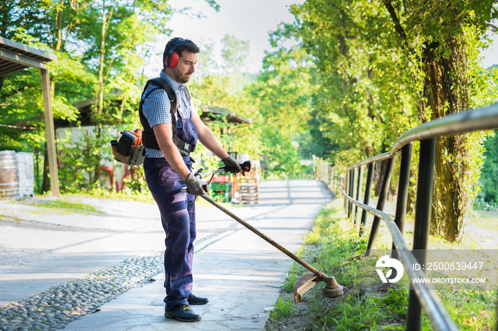 Professional gardener using an edge trimmer in home garden