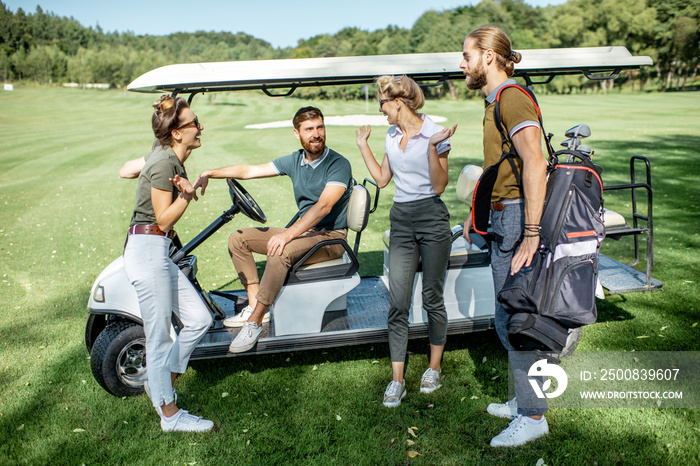 Group of a young friends hanging out together with golf equipment near the golf car on the playing course before the game