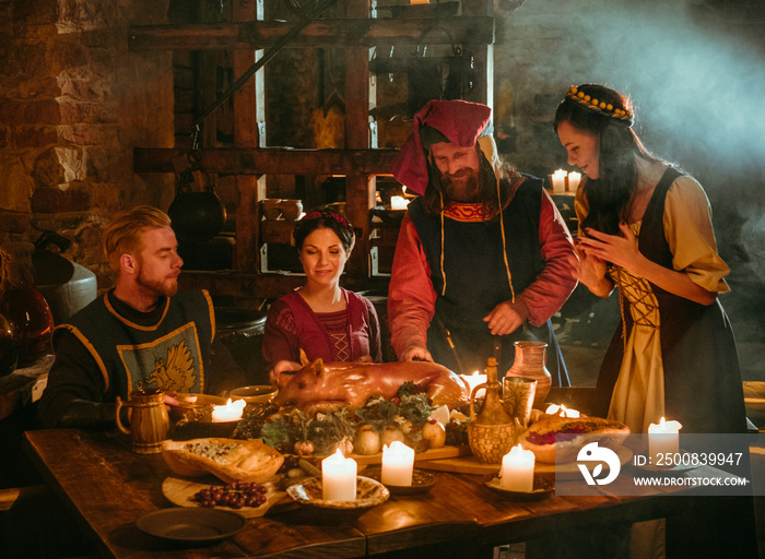 Medieval people eat and drink in castle tavern.