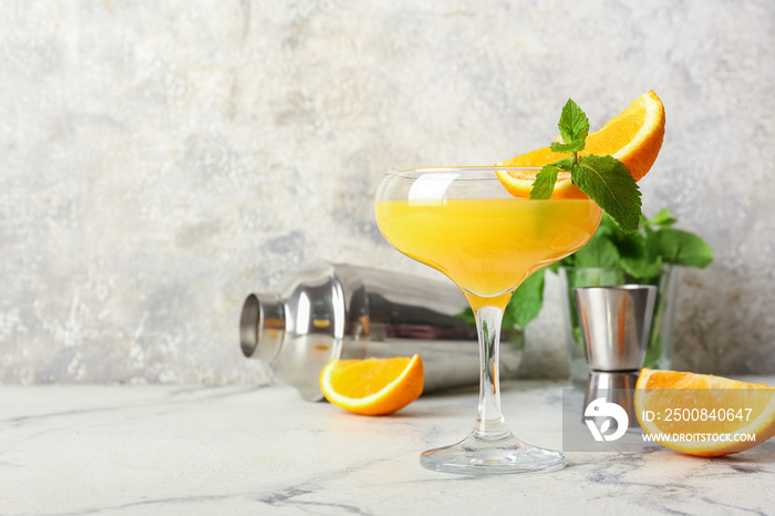 Glass of orange margarita cocktail on light background