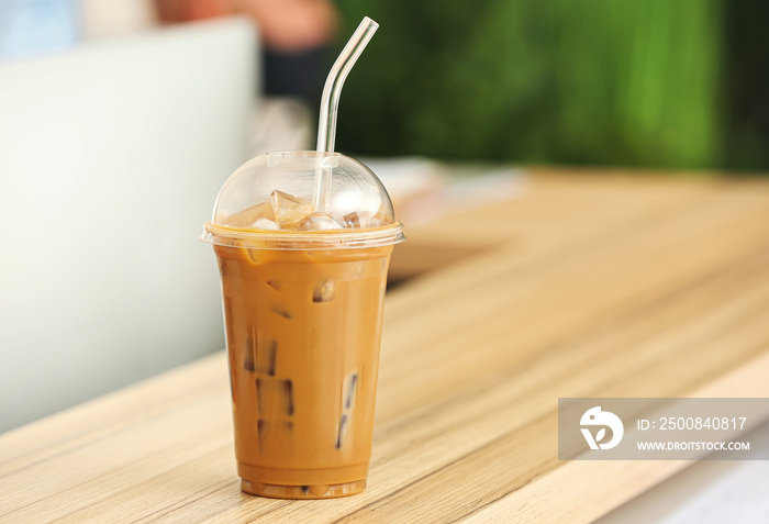 Cup of tasty iced coffee on table in room, closeup