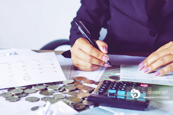 business woman hand calculating her monthly expenses during tax season with coins, calculator, credit card and account bank, idea for dept collection background