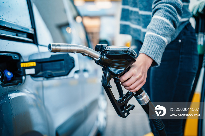 Closeup of woman pumping gasoline fuel in car at gas station. Petrol or gasoline being pumped into a motor. Transport concept