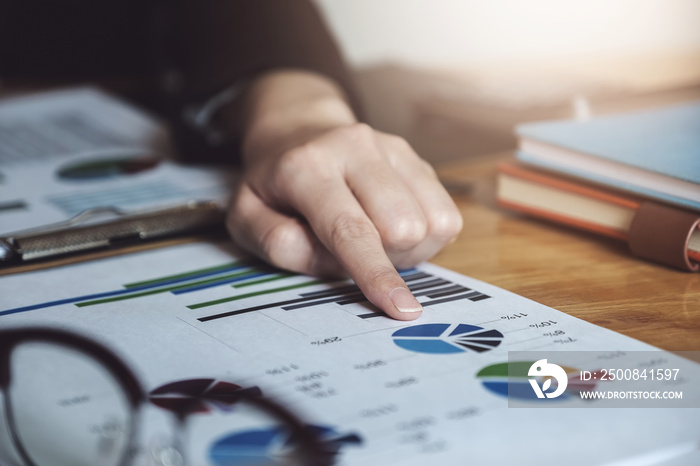 Business woman point to documents that have graphs showing the investment market share balance sheet annual in meeting room.