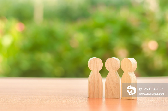 three wooden figures of people stand on the background of nature. Communication, meeting place. conduct a conversation. Discussion of cases and plans, society and community. Place for text.