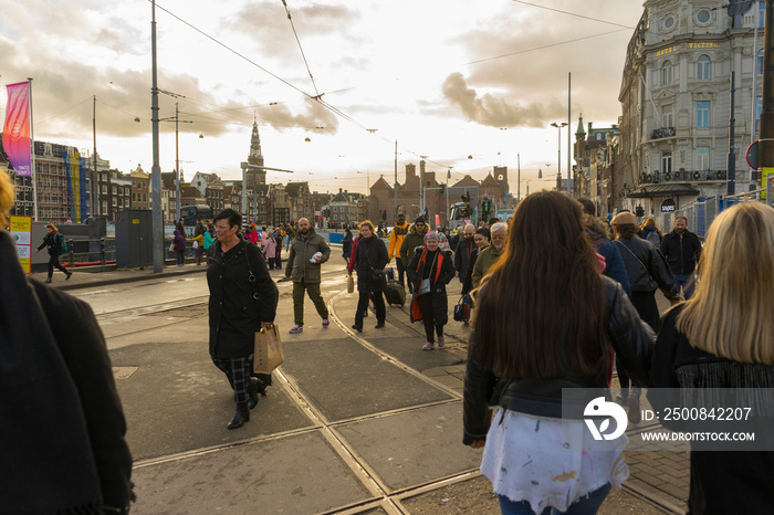 Crowd of people walking on the street in front of Amsterdam Central station at twilight in Amsterdam, Netherlands