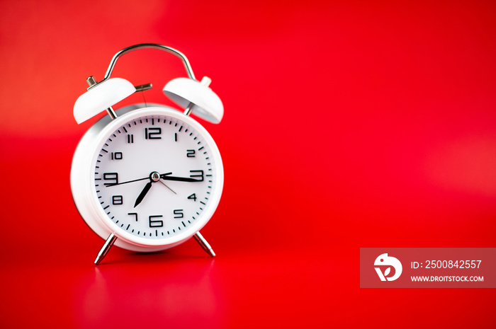 white alarm clock on red background time concept