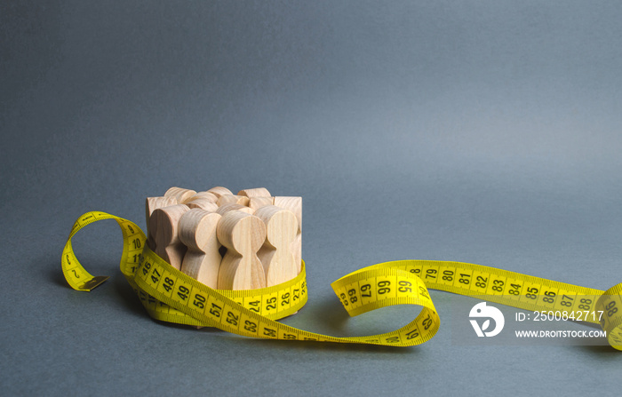 A crowd of wooden figures Gripped by measuring tape. Information statistics, measurement of the number, trends of population growth. Social Sciences. Promotion of ideas for weight loss, lifestyle