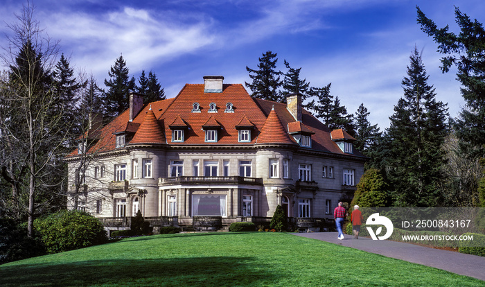 Two motion blurred people (slow shutter speed to show movement) walking on a path to  Pittock Mansion which is a historic house museum in Portland Oregon.