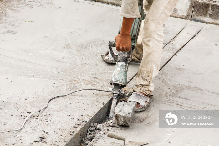 Construction worker using jackhammer drilling concrete surface