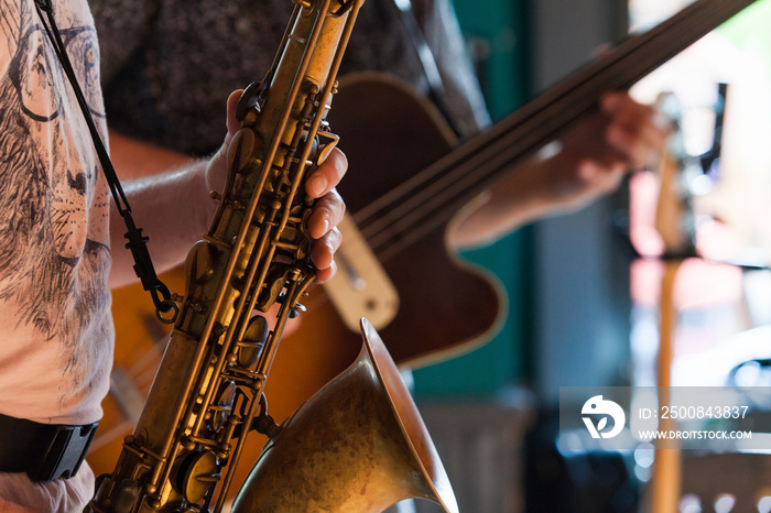 Tenor Saxophone player is playing a jazz solo in a pub - Closeup picture with a blurry fretless bassist playing in the background