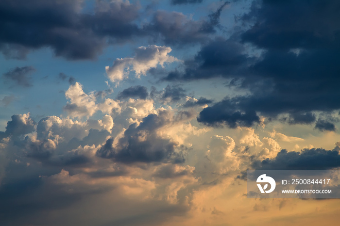 Cloudy sky at sunset. Cumulus clouds painted in golden and blue colors. Dramatic heavenly landscape.