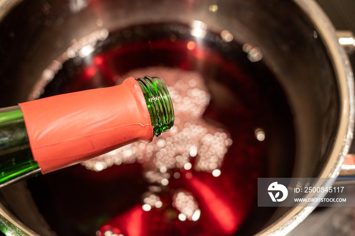 a mulled wine is poured into a saucepan to heat it up